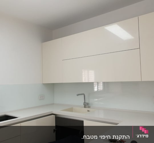 חיפוי זכוכית לבן במטבח מודרני עם כיור וברז